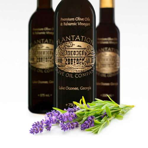 Photo showing a fresh sprig of lavender in front of three bottles of dark balsamic vinegar.
