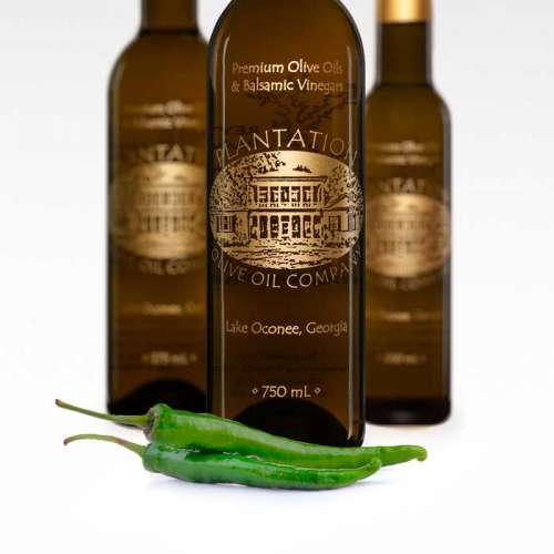 Photo showing fresh Baklouti peppers in front of three bottles of olive oil.