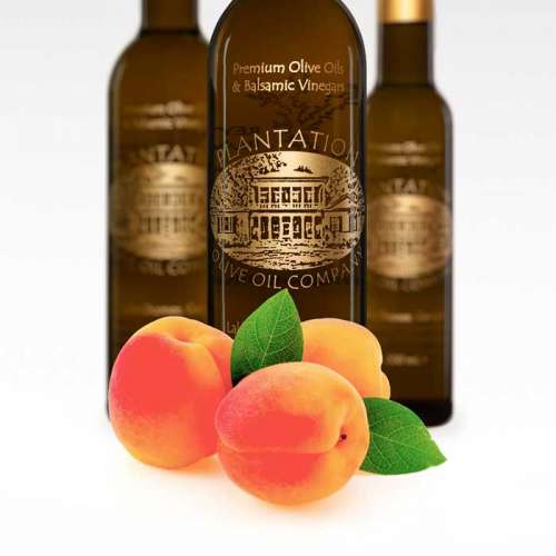 Photo showing fresh picked Blenheim apricots in front of three bottles of white balsamic vinegar.