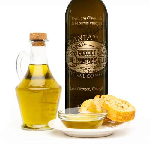 Photo showing olive oil dispenser bottle and dipping bread in front of large bottle of Plantation olive oil.