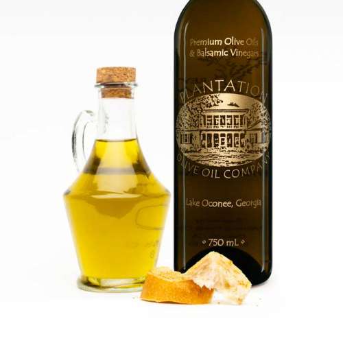 Photo showing olive oil dispenser bottle and dipping bread in front of large bottle of Plantation olive oil.