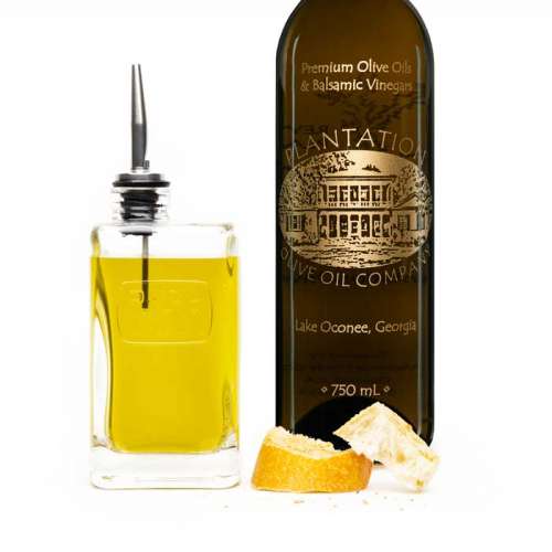 Photo showing olive oil dispenser bottle and dipping bread in front of large bottle of Plantation olive oil.