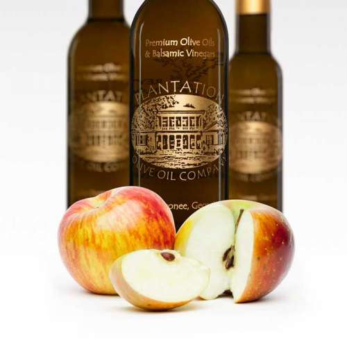 Photo of fresh Gravenstein apples in front of 3 bottles of white balsamic vinegar.