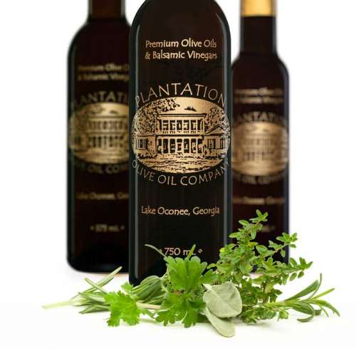 Photo of fresh green garden herbs in front of three bottles of dark balsamic vinegar.