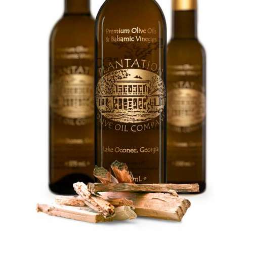 Photo showing small chunks of olive tree wood in front of three bottles of olive oil.
