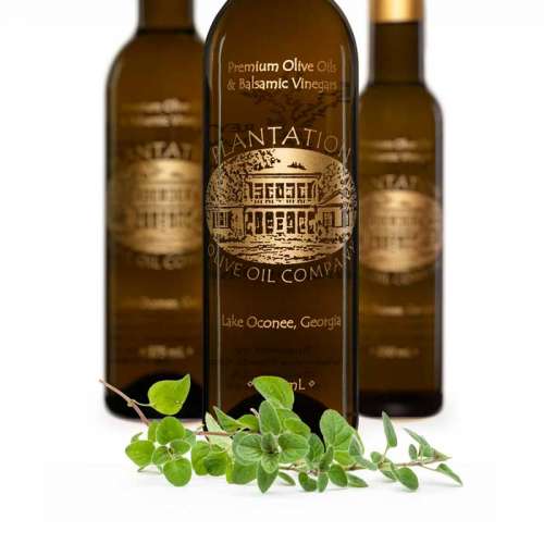 Photo showing fresh oregano leaves in front of three balsamic vinegar bottles.