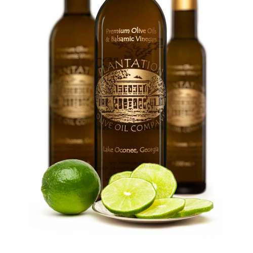 Photo showing whole Persian lime next to sliced lime in front of three bottles of olive oil.