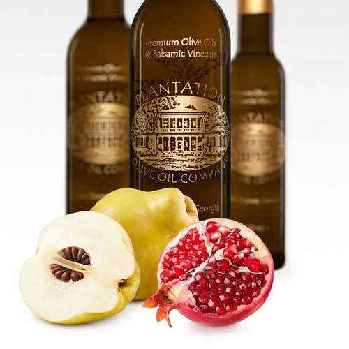 Photo showing Quince fruit and pomegranate fruit in front of three balsamic vinegar bottles.
