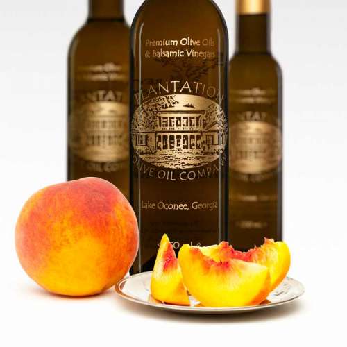 Photo showing whole peach and peach slices in front of three bottles of white balsamic vinegar