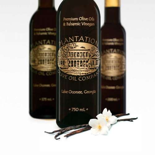 Photo showing vanilla beans and flower in front of three balsamic vinegar bottles.