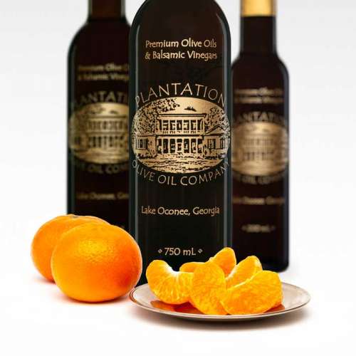 Photo showing fresh whole and sliced tangerines in front of three bottles of dark balsamic vinegar.
