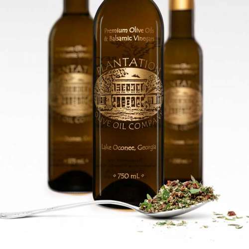 Photo showing fresh tuscan herbs in front of three bottles of olive oil.