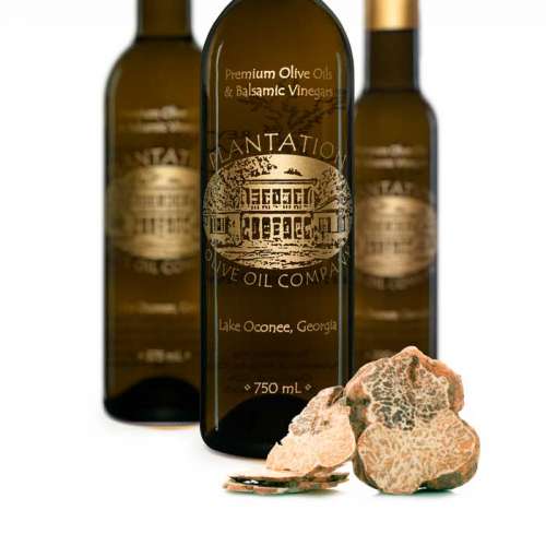 Photo showing fresh truffles in front of three bottles of olive oil.