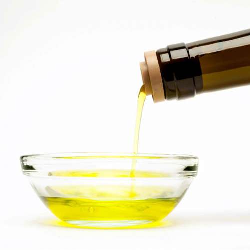 Photo of olive oil pouring gently from the tan rubber Tapi Pour Spout into a bowl.